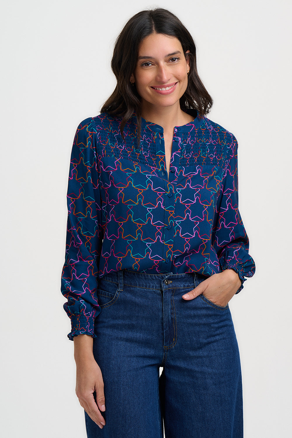 Woman wearing a blue patterned blouse and jeans on a white background