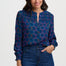 Woman wearing a blue patterned blouse and jeans on a white background