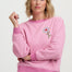 Woman wearing a pink sweatshirt with a floral design on a white background
