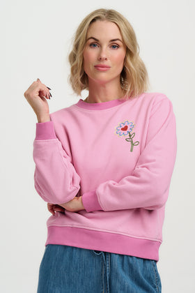 Woman wearing a pink sweatshirt with a floral design on a white background