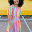 A woman smiling and wearing a multicolored tiered midi jersey dress with a round neckline and short puff sleeves.