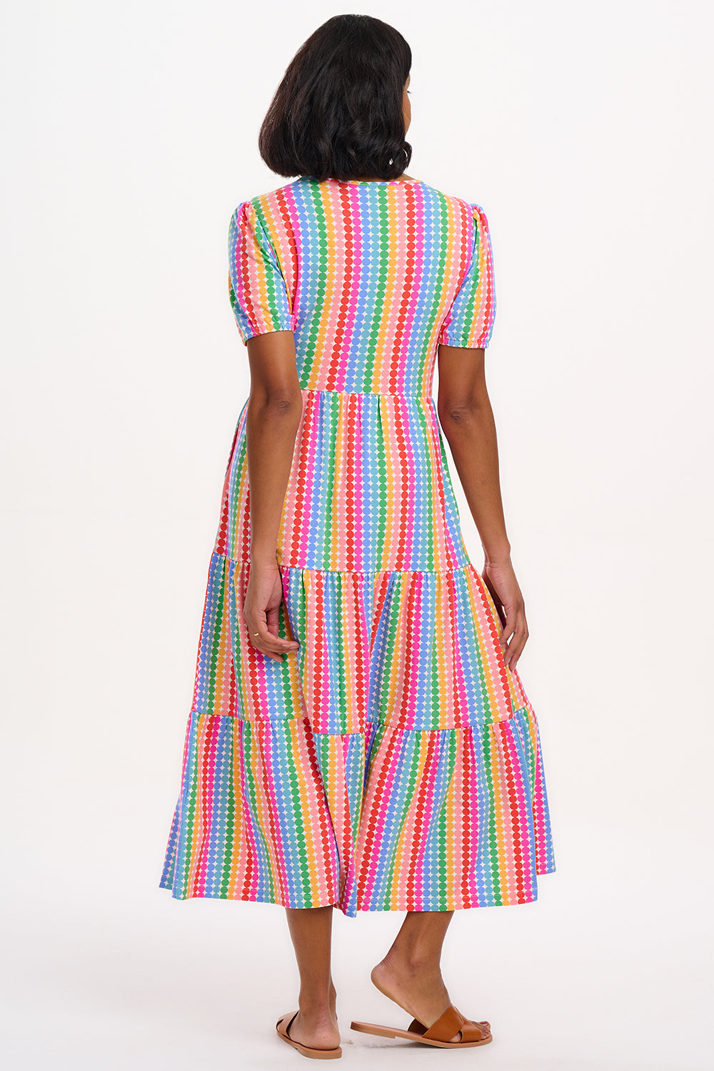 A model wearing a midi length tiered dress with a multicolored geometric pattern.