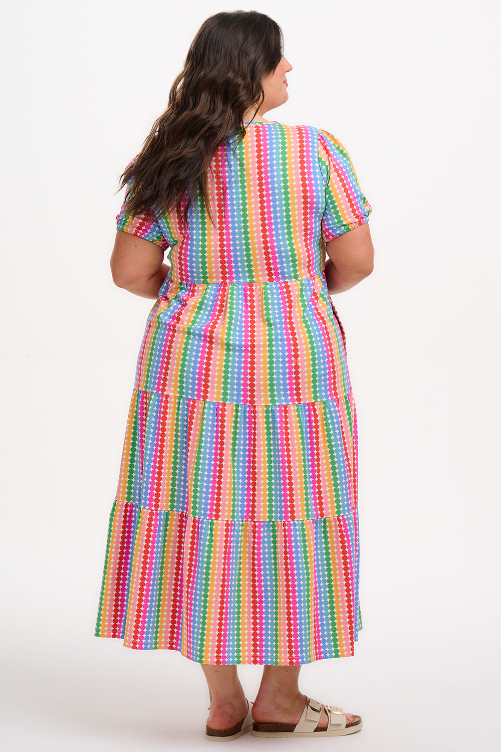 A model wearing a midi length tiered dress with a multicolored geometric pattern.