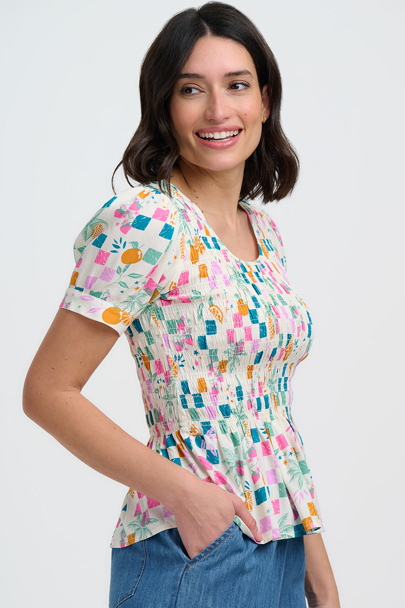 Woman wearing a colorful patterned shirt and blue jeans on a white background