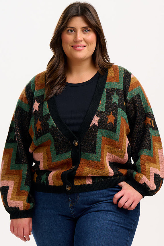 Woman wearing a patterned cardigan with stars and zigzag design on a white background