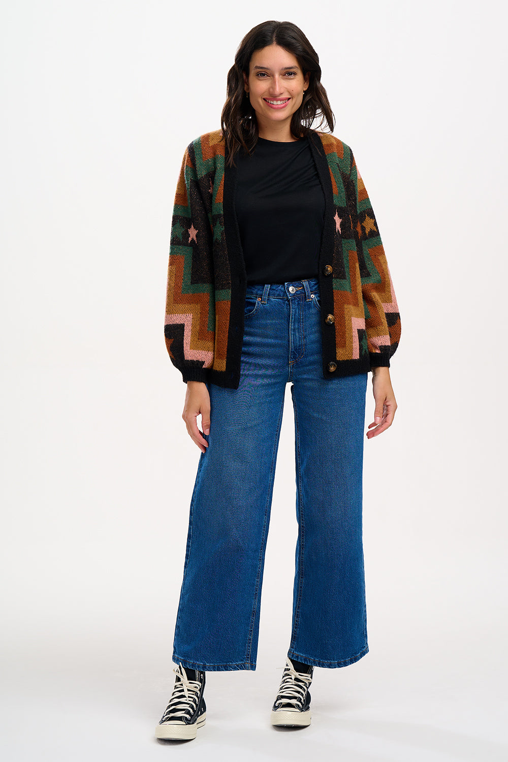 A woman wearing a multicolored geometric patterned cardigan with button front and long blouson sleeves.