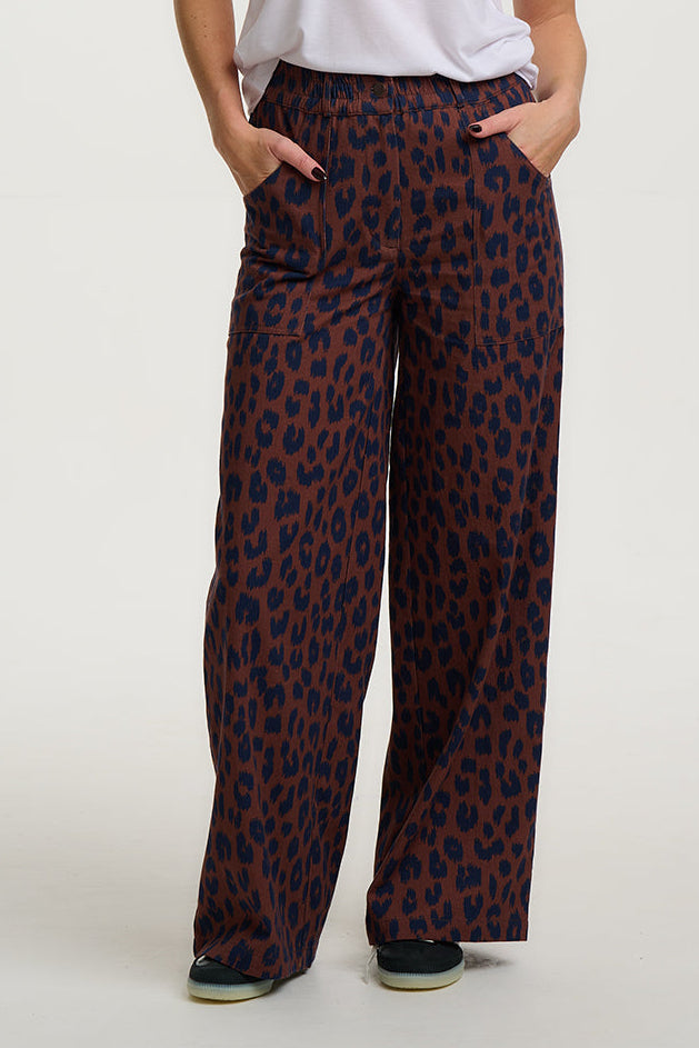 Person wearing leopard print pants on a plain background