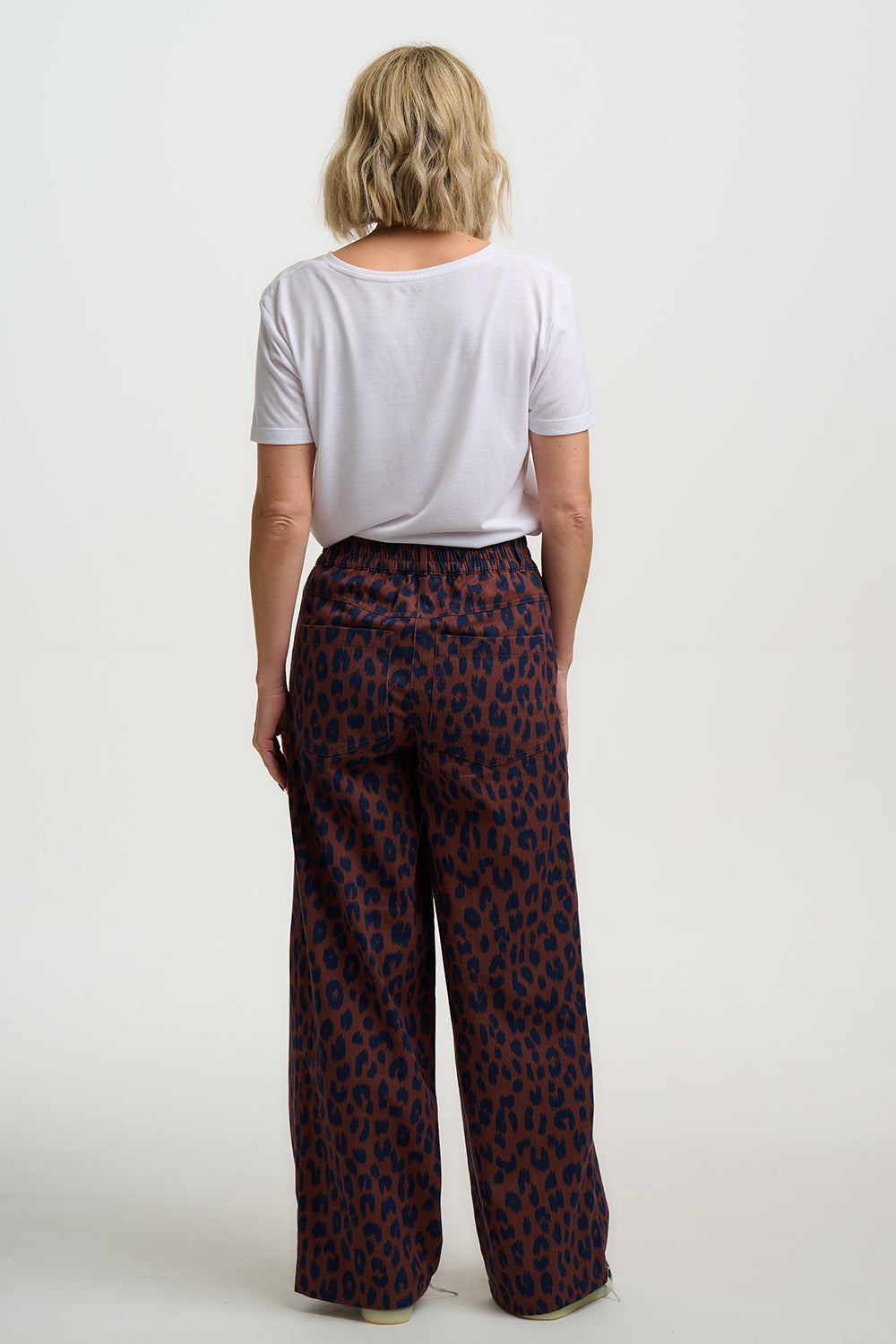 Person wearing a white t-shirt and patterned pants on a plain background