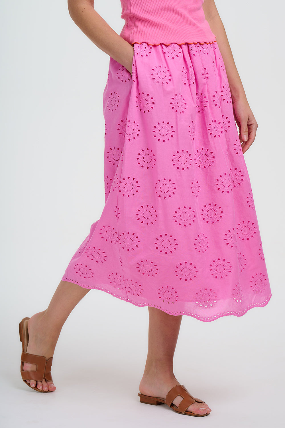 Person wearing a pink skirt with floral cut-out pattern on a white background
