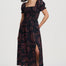 Woman wearing a black dress with pink floral pattern on a white background