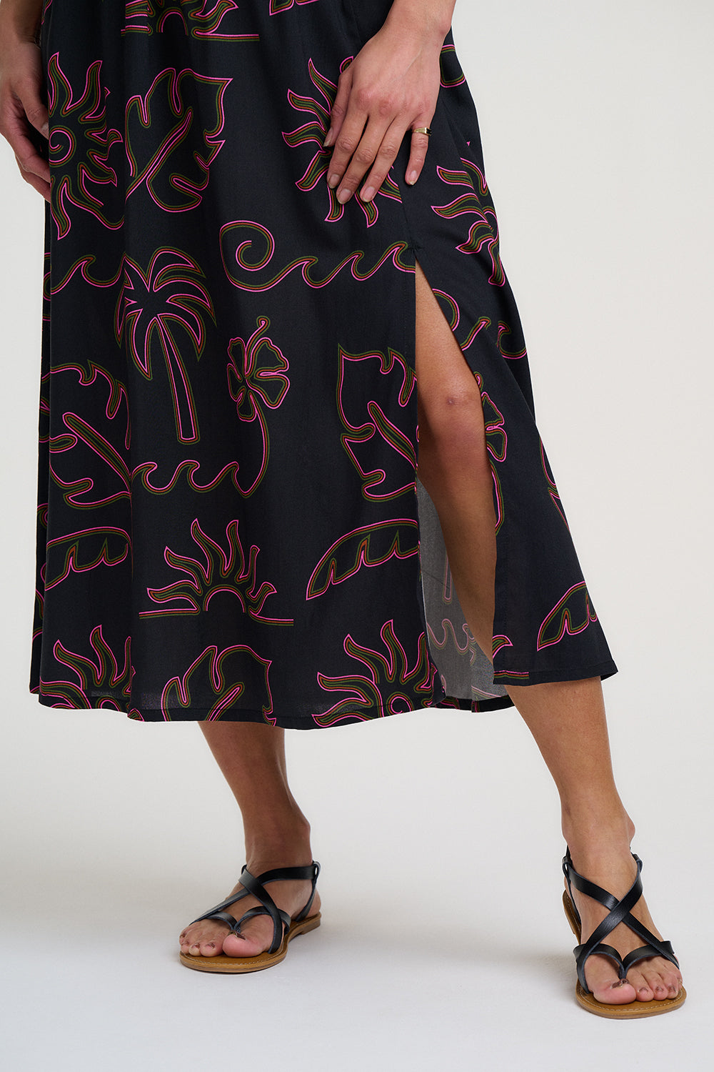 Person wearing a black dress with red floral patterns on a white background