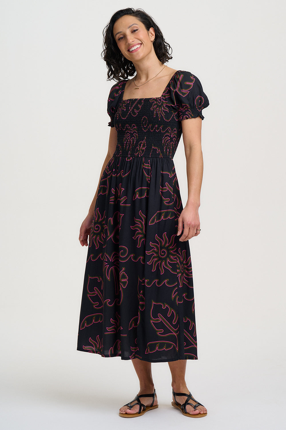 Woman wearing a black dress with red floral patterns on a white background