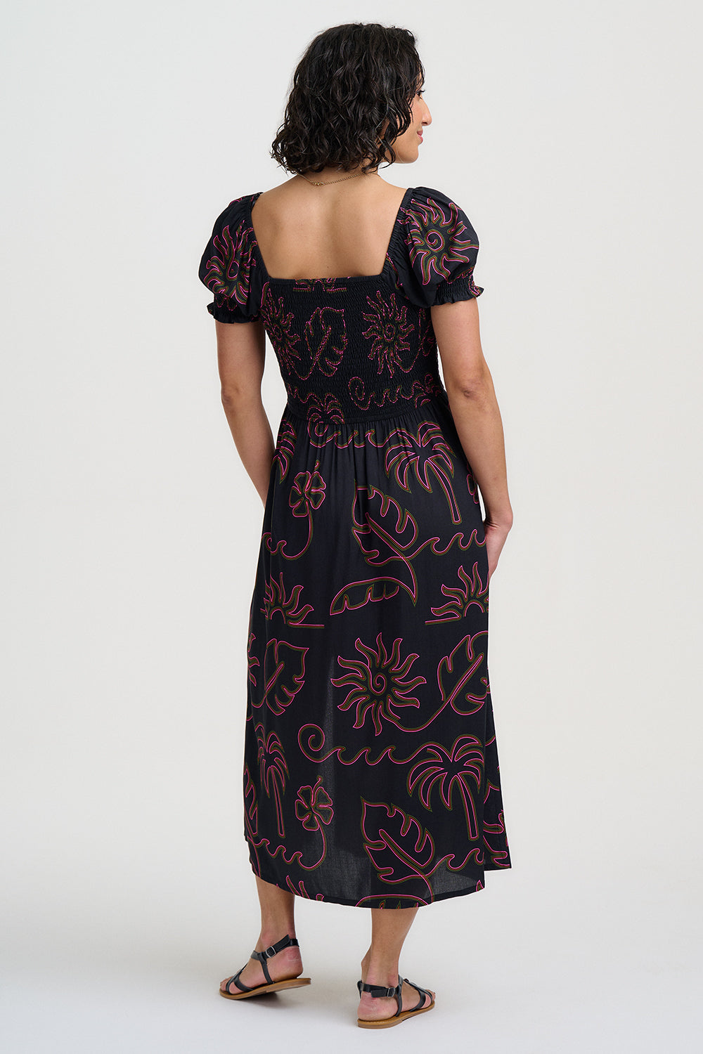 Woman wearing a black dress with red floral patterns on a white background