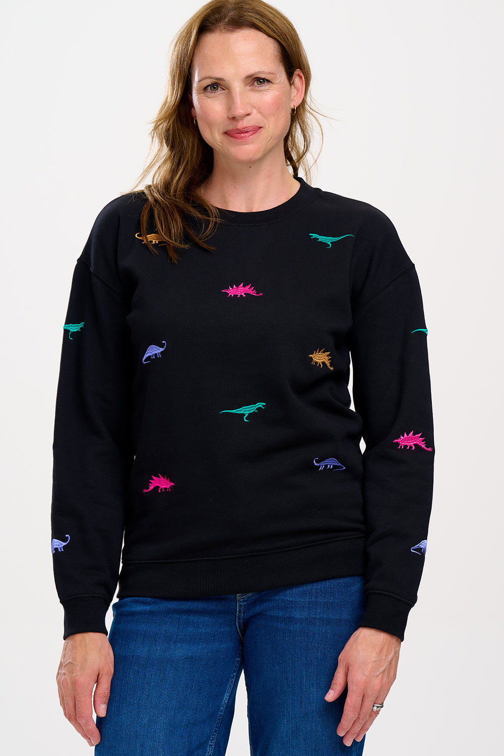 A woman wearing a black sweatshirt with multicoloured embroidered dinosaurs