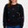 A woman wearing a black sweatshirt with multicoloured embroidered dinosaurs