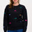 A woman wearing a black sweatshirt with multicoloured embroidered dinosaurs