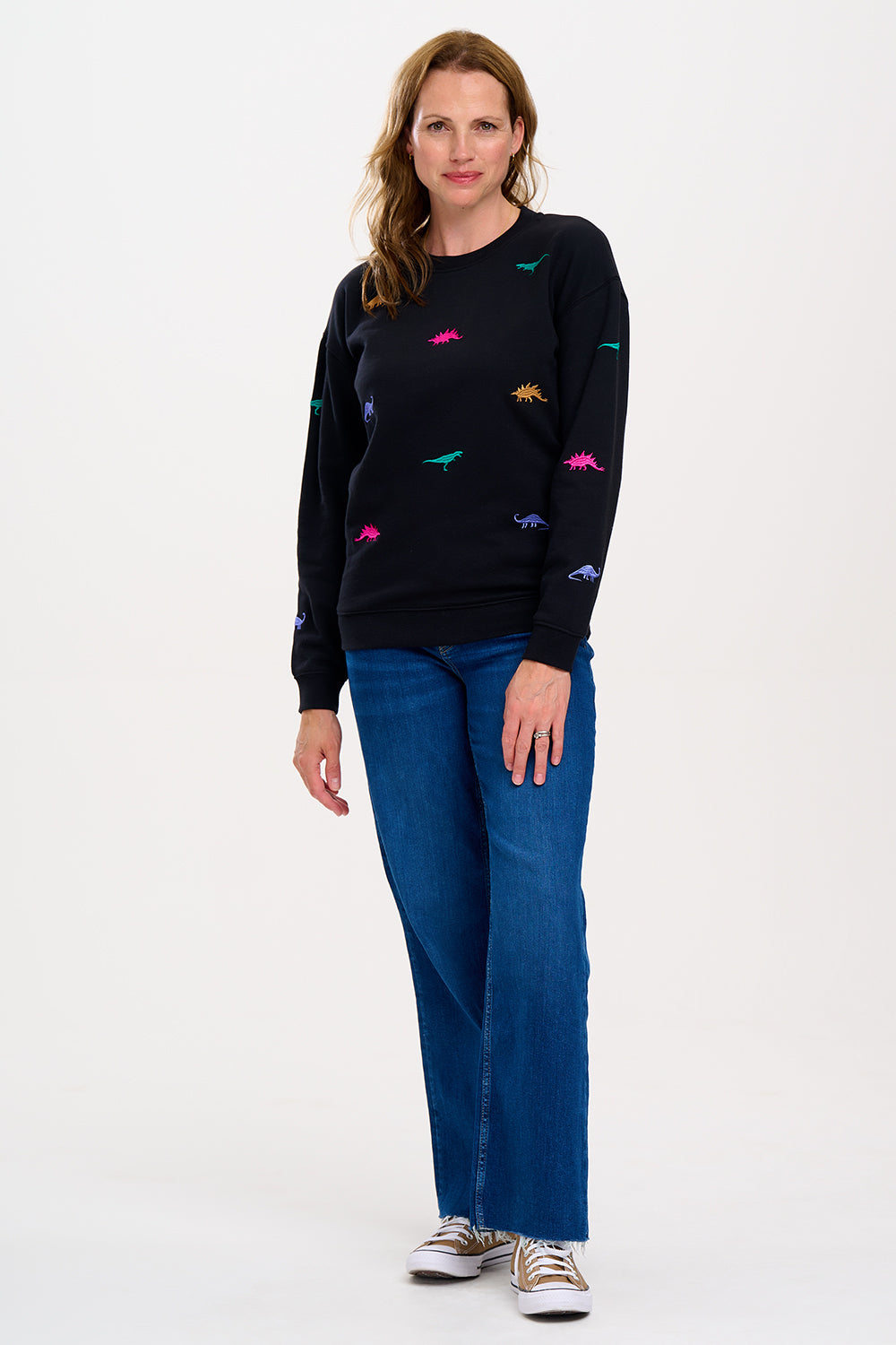 A woman wearing a black sweatshirt with multicoloured embroidered dinosaurs