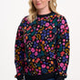 Woman wearing a colorful floral-patterned sweater on a white background