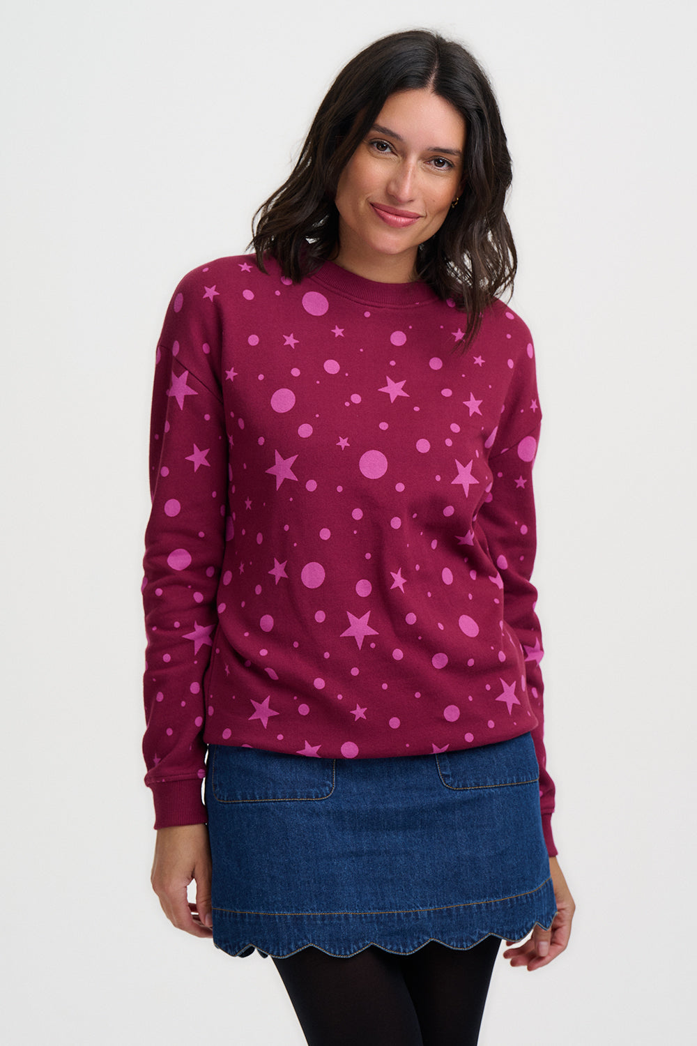 Woman wearing a maroon sweater with pink star pattern on a white background