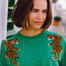 A woman wearing a green sweatshirt with embroidered tigers climbing the shoulders.