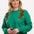 A woman wearing a green sweatshirt with embroidered tigers climbing the shoulders.