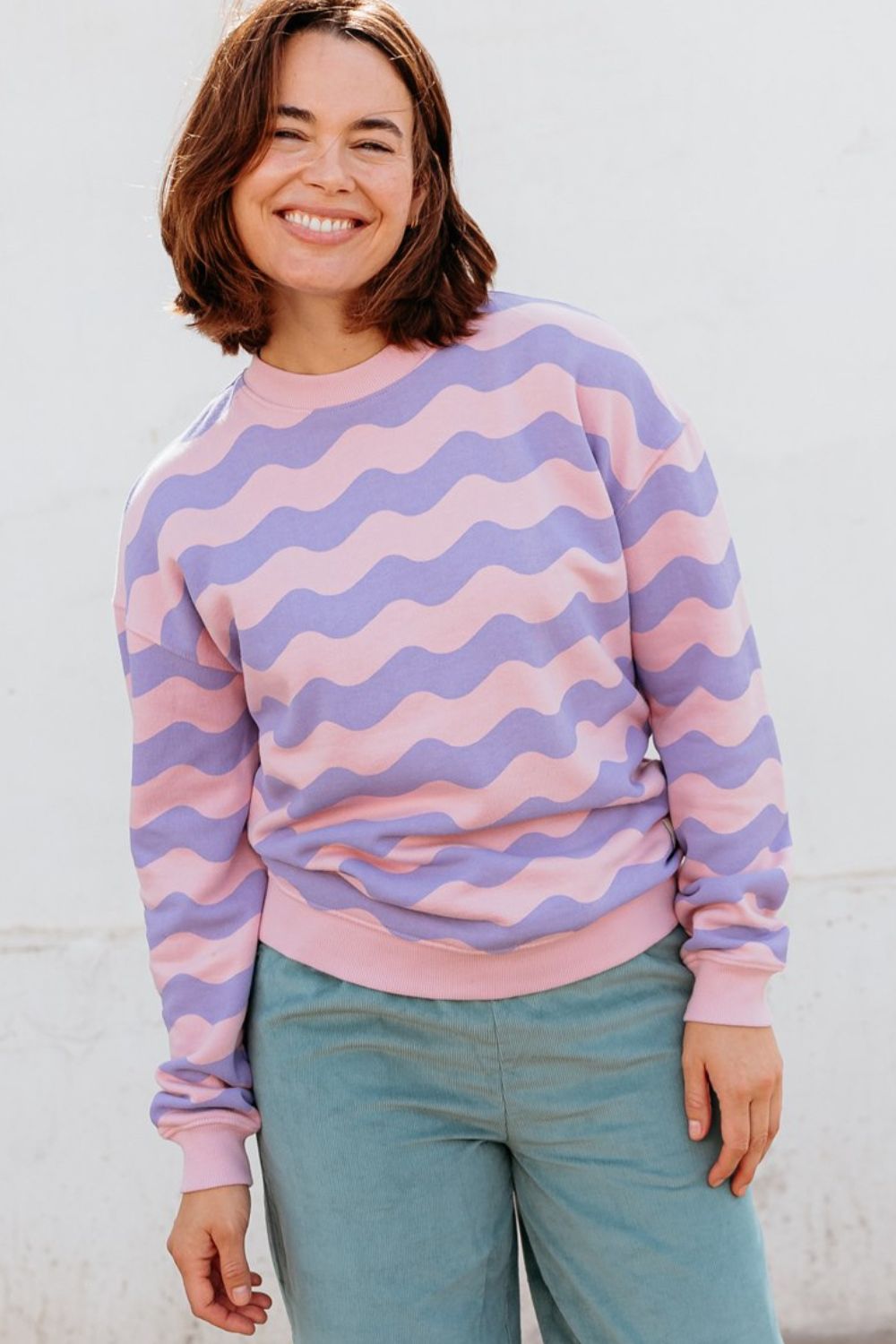 Person wearing a pink and purple striped sweater against a white background