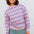 Person wearing a pink and purple striped sweater against a white background