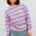 Person wearing a pink and purple striped sweater against a white background