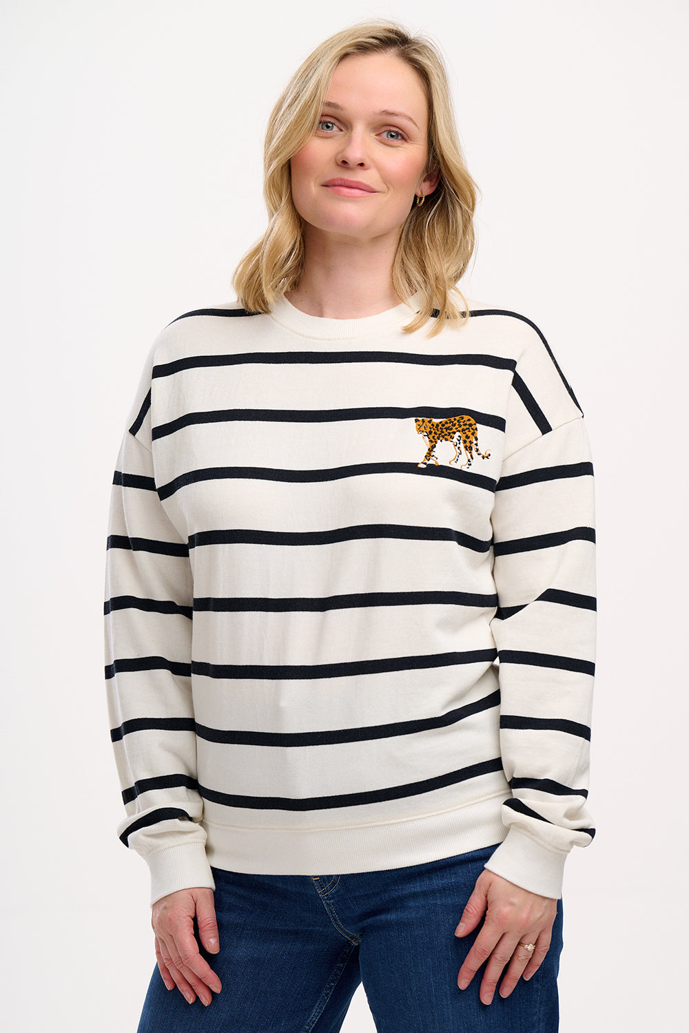 A female model wearing an off-white and black striped Noah sweatshirt with leopard embroidery on the chest.