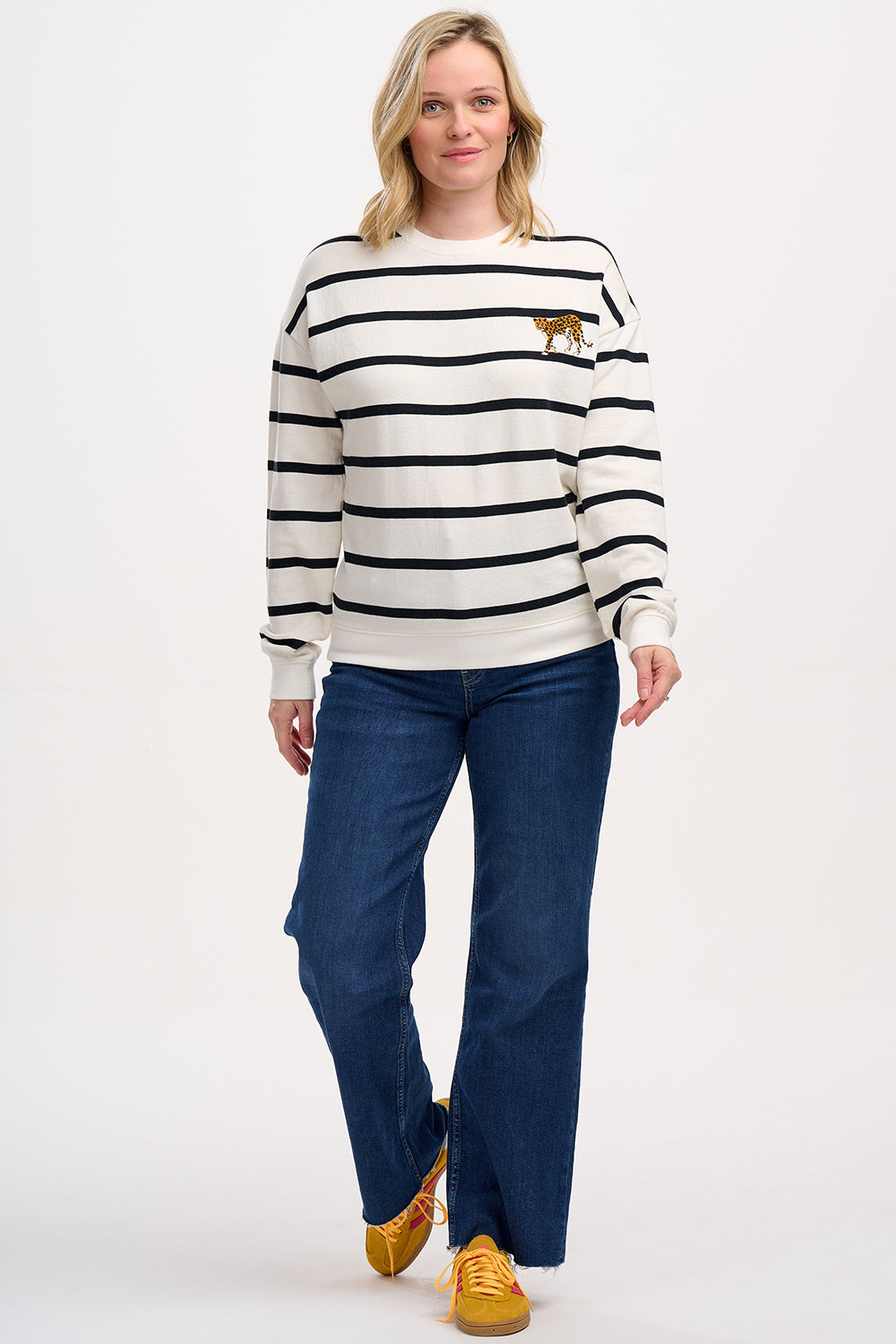 A female model wearing an off-white and black striped Noah sweatshirt with leopard embroidery on the chest.