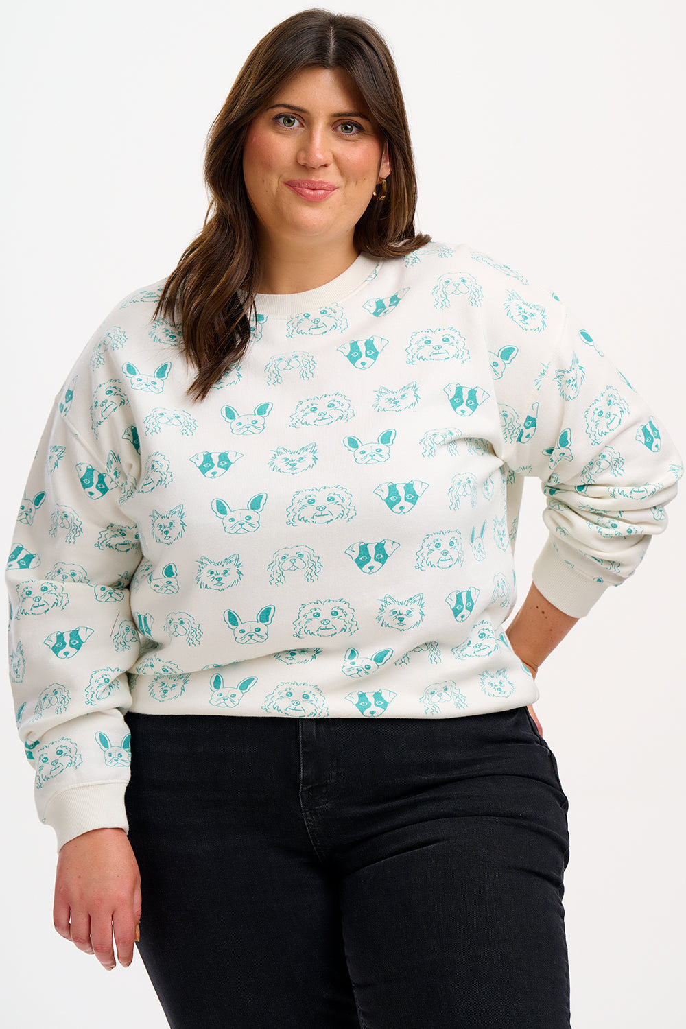 A woman wearing an off-white sweatshirt with a pattern of sketched dog faces in green.