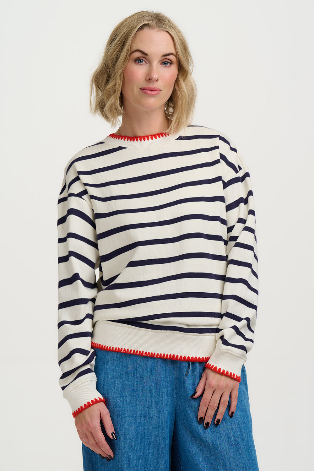 Woman wearing a striped sweater and blue jeans on a white background