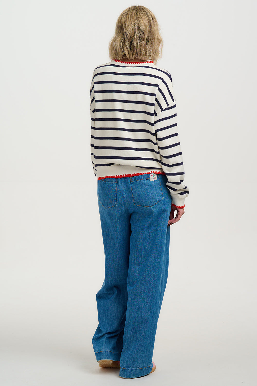 Person wearing a striped sweater and blue jeans on a white background