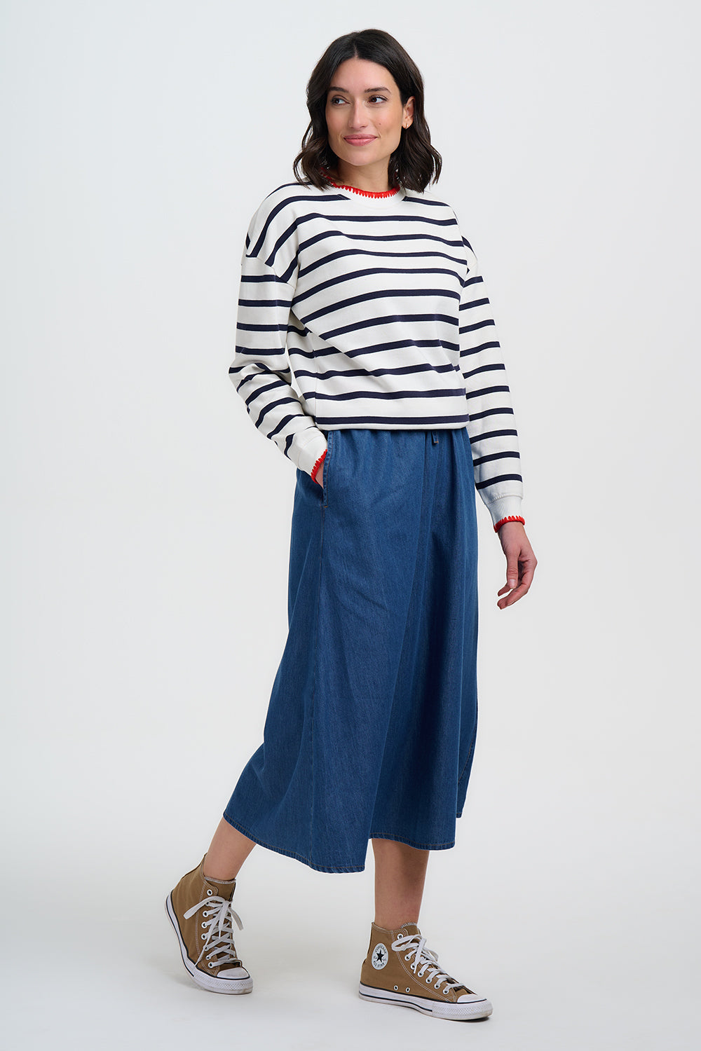 Woman wearing a striped sweater and blue pants on a white background