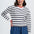 Woman wearing a striped sweater and blue pants on a white background