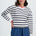 Woman wearing a striped sweater and blue pants on a white background