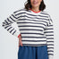 Woman wearing a striped sweater and blue pants on a white background