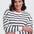 Woman wearing a striped sweater with red accents on a white background