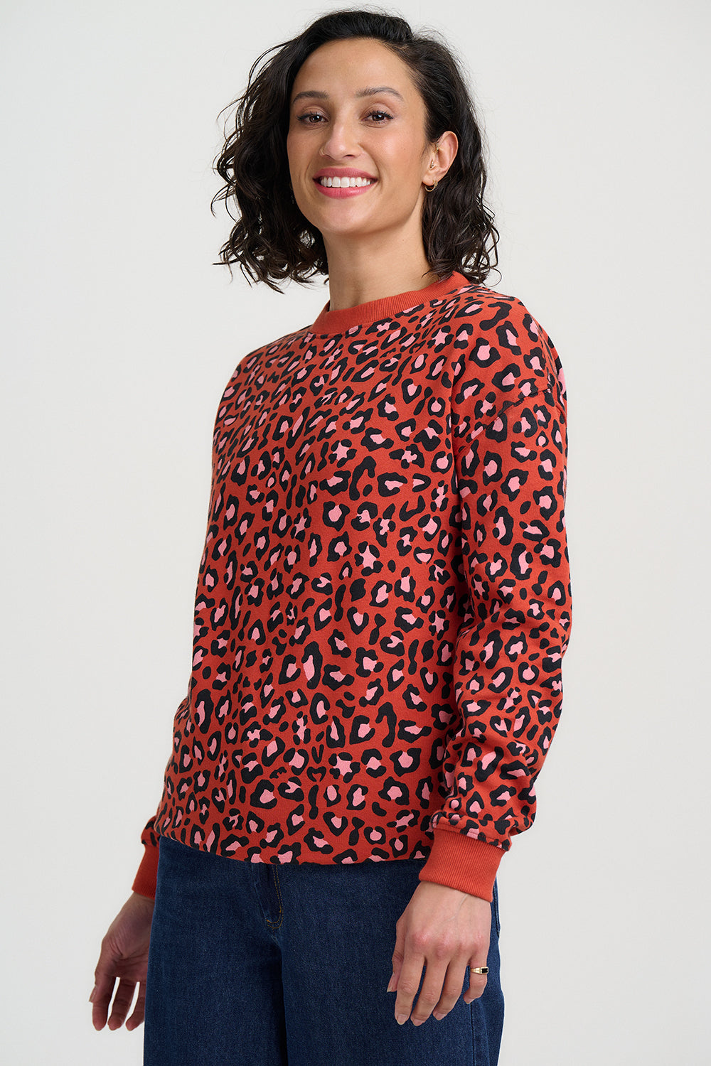 Woman wearing a red sweater with a black and pink leopard print pattern on a white background