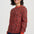 Woman wearing a red sweater with a black and pink leopard print pattern on a white background