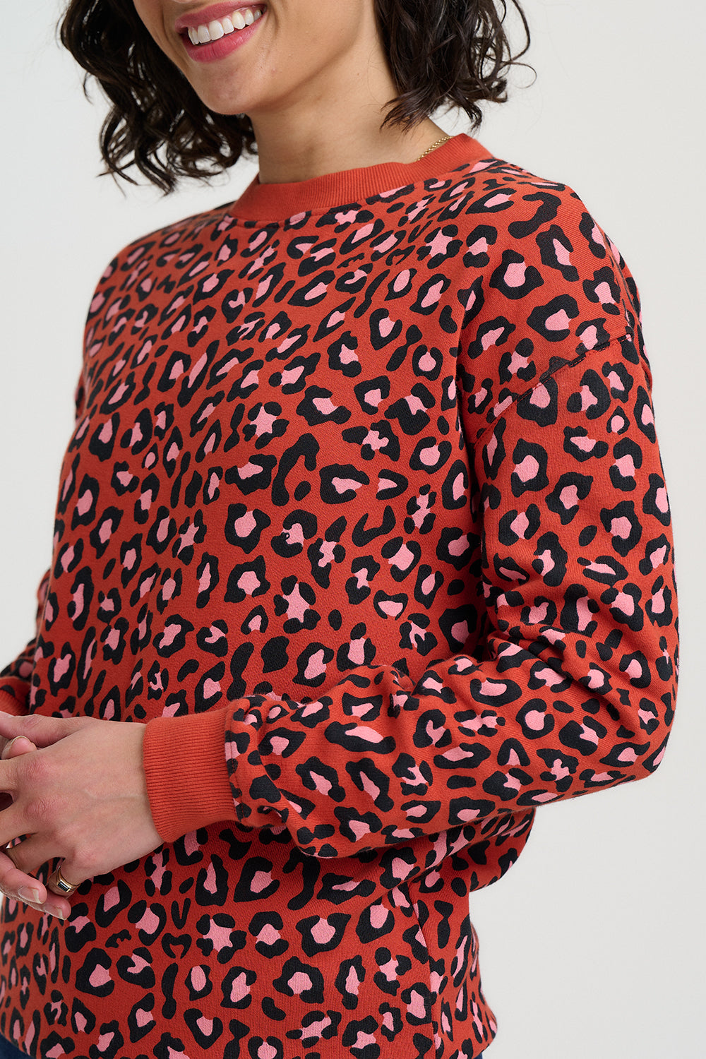 Person wearing a red sweater with a leopard print pattern on a white background