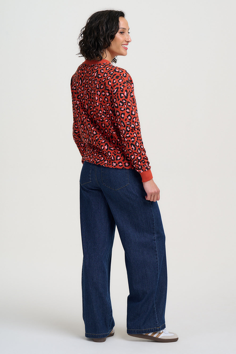 Person wearing a red leopard print top and blue jeans on a white background