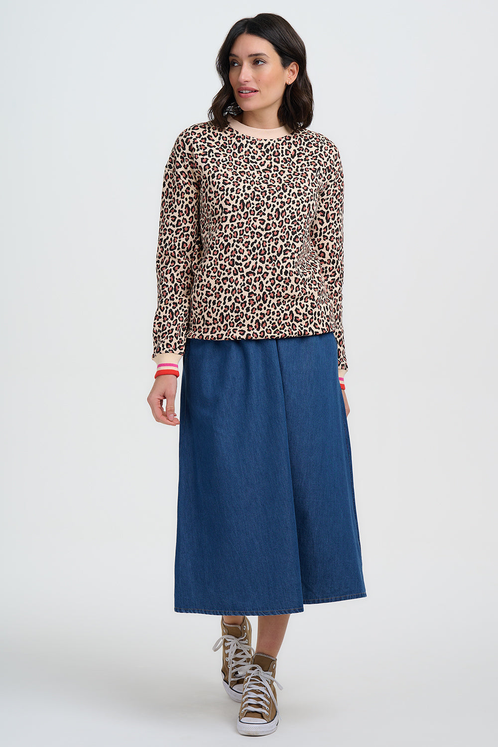 Woman wearing a leopard print top and blue skirt on a white background