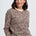 Woman wearing a leopard print sweater against a plain background