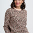 Woman wearing a leopard print sweater against a plain background