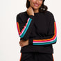 Woman wearing a black outfit with colorful stripes on a white background
