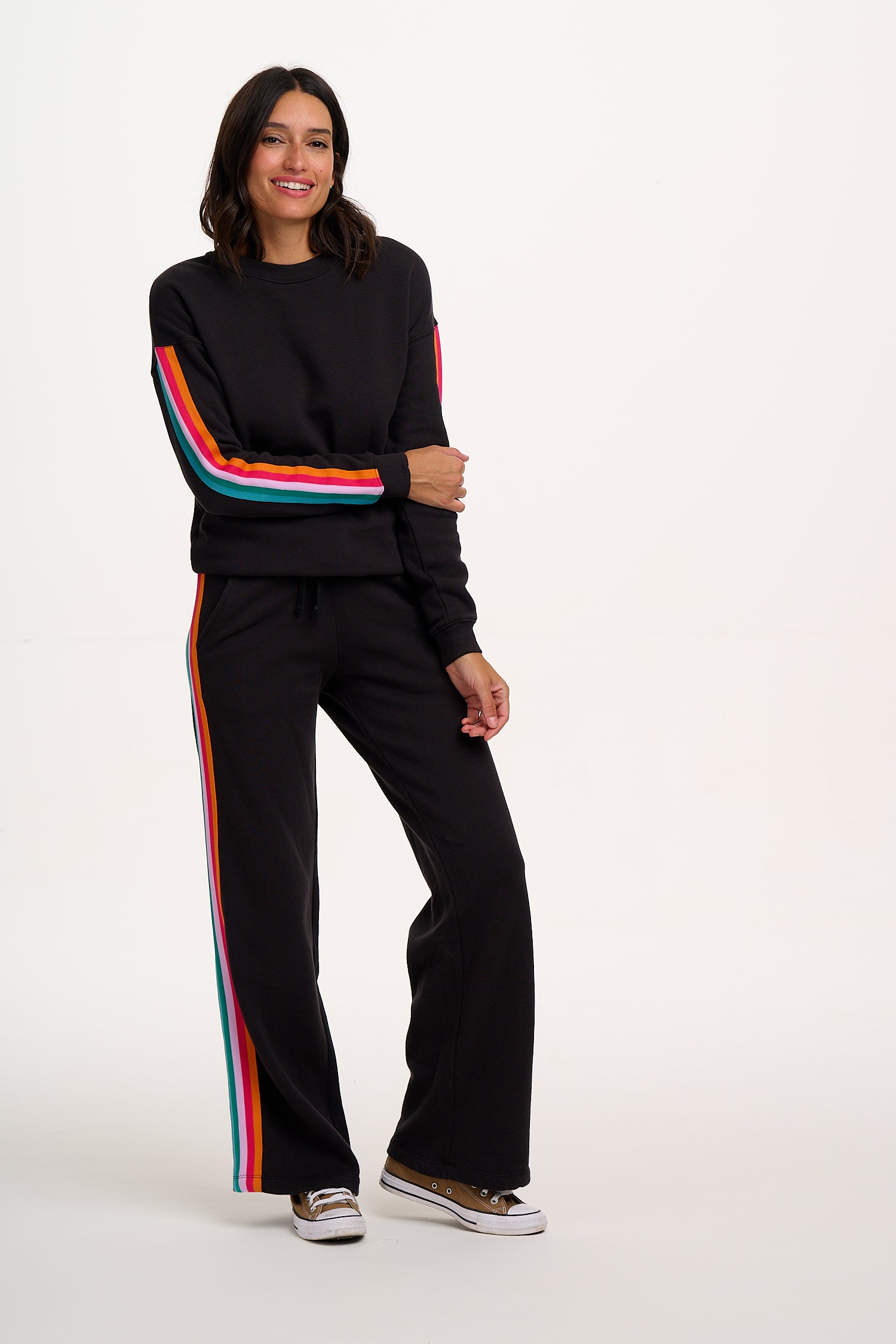 Woman wearing a black tracksuit with colorful stripes on a white background