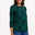 Woman wearing a green patterned top and blue jeans on a white background