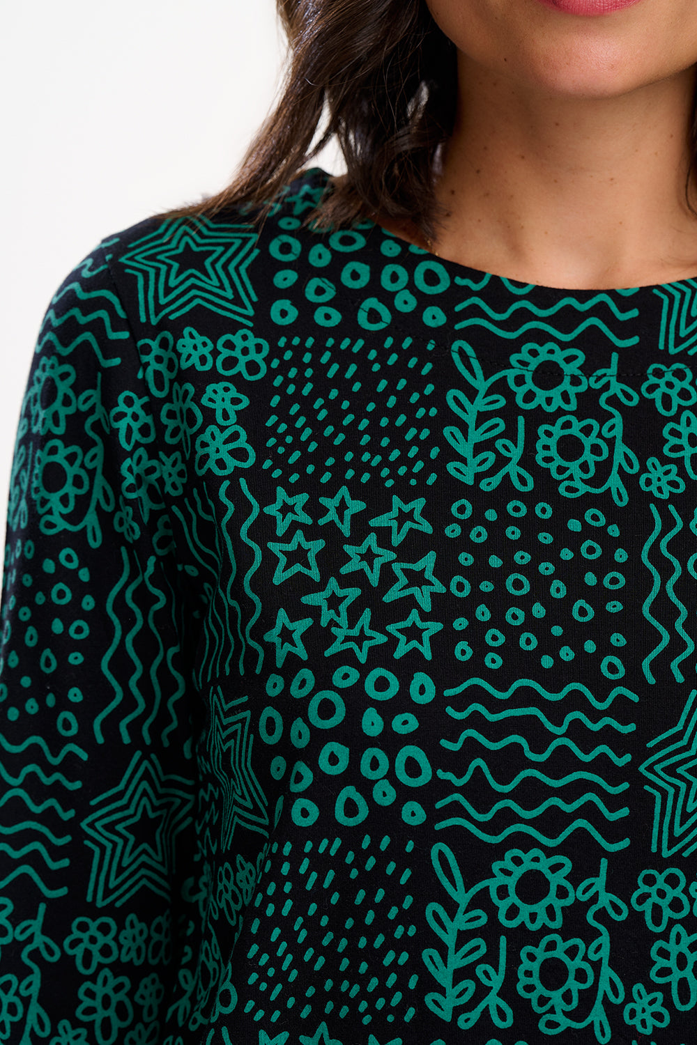 Close-up of a person wearing a black sweater with teal geometric pattern