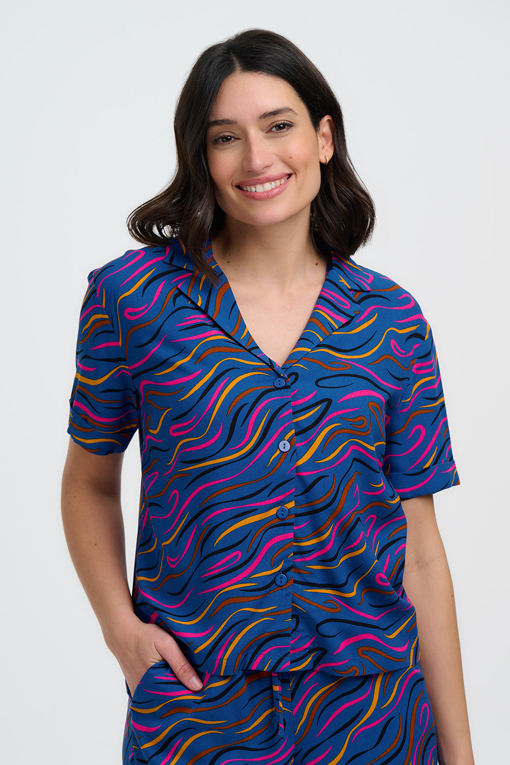Woman wearing a colorful patterned shirt and pants on a white background